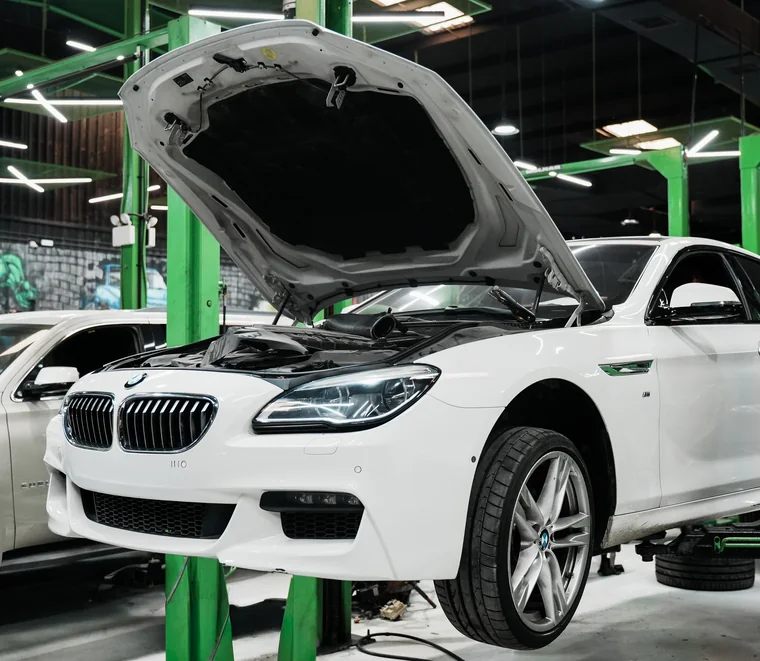 Engine bay inspection under way on a BMW raised on a lift in the Mussafah workshop