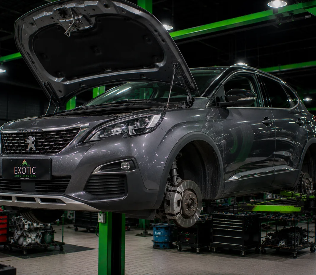 A car on a two-post lift with the wheels off, in the Mussafah workshop